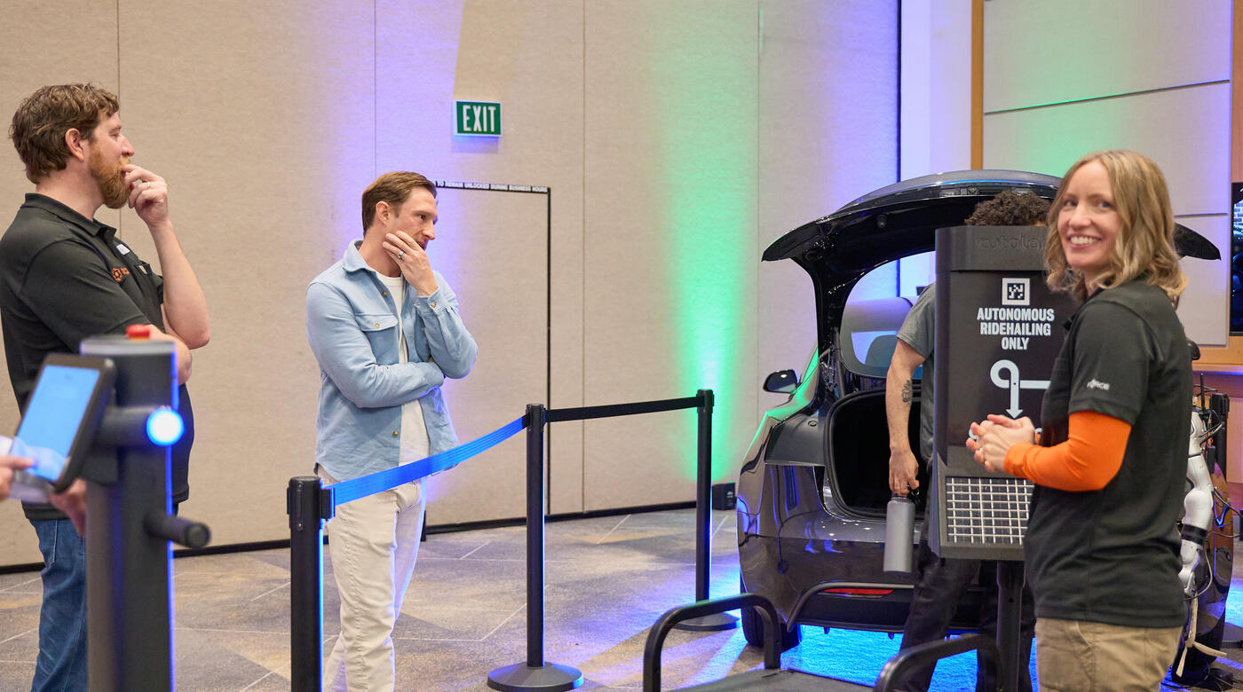 Duncan Miller, Ben Seidl, and Aaryn Curl in conversation at the Autolane exhibit during Silicon Forest Tech Summit 2026, with Kaj Hansteen-Izora visible in the background behind the booth signage.