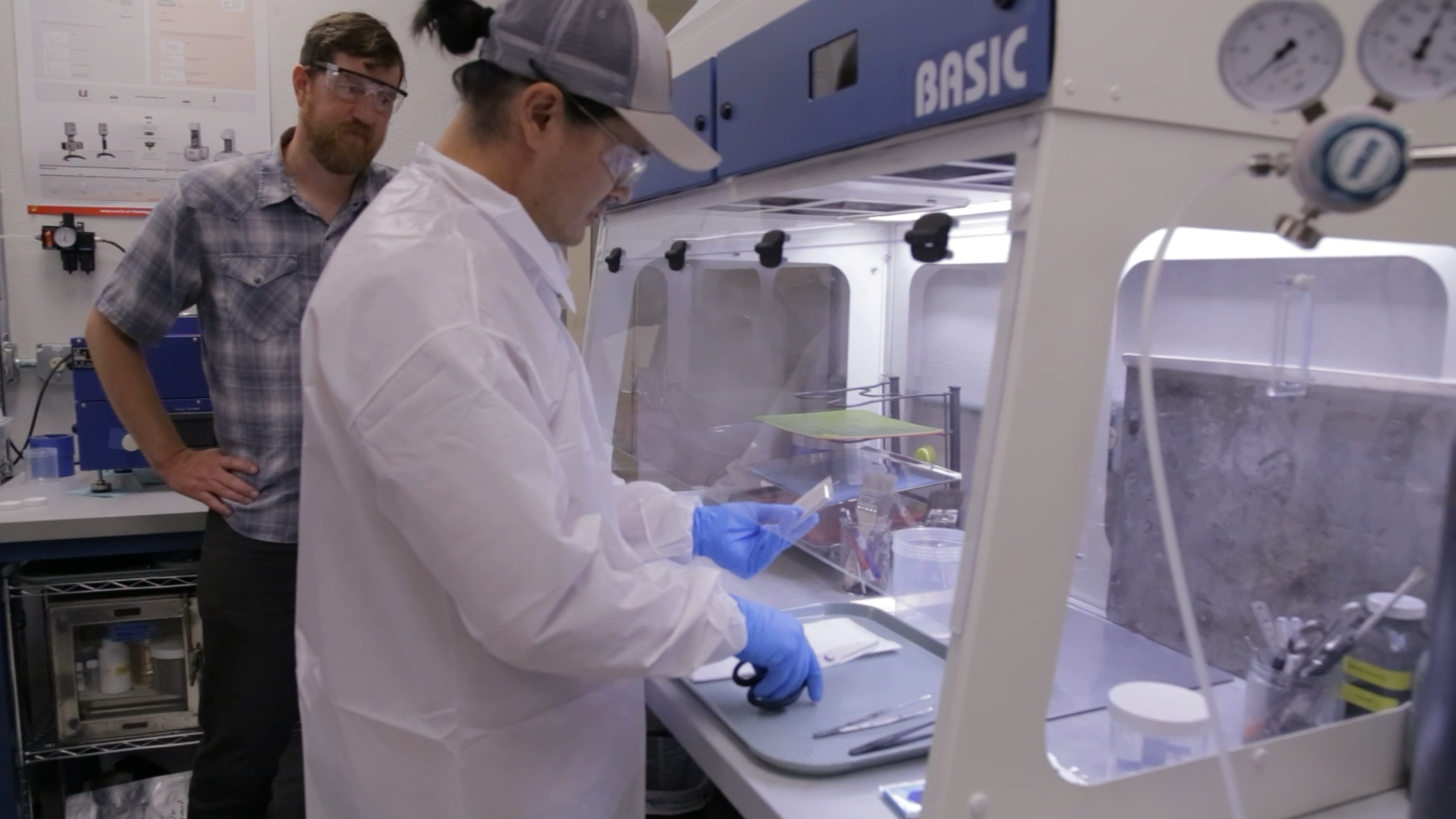 Engineers manually inspecting cells in a glovebox