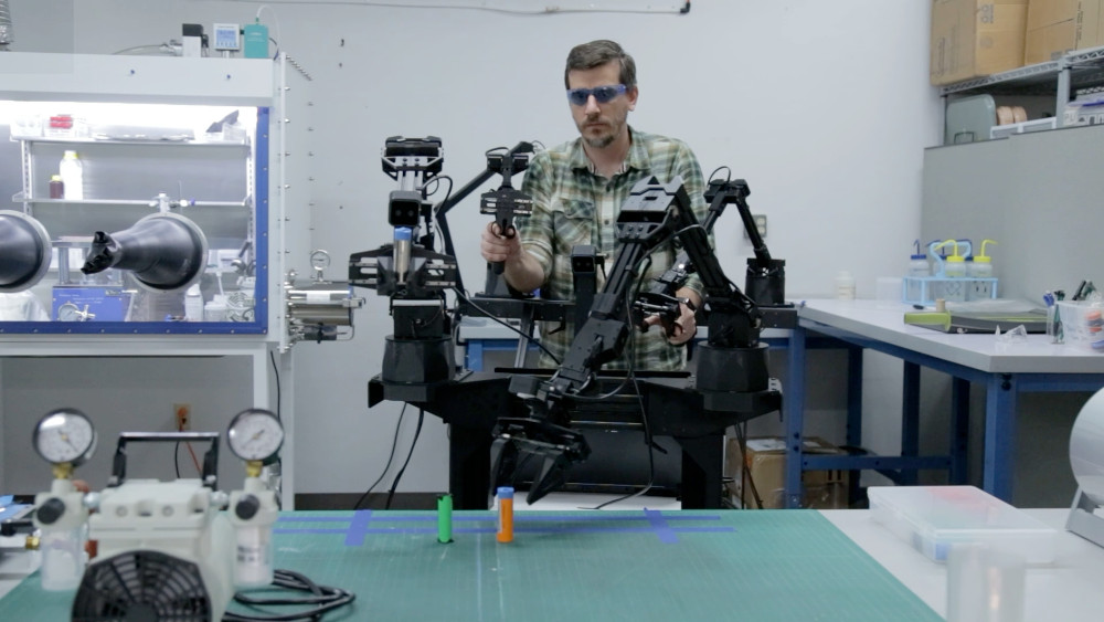 Joseph Cole with robot in the battery research lab